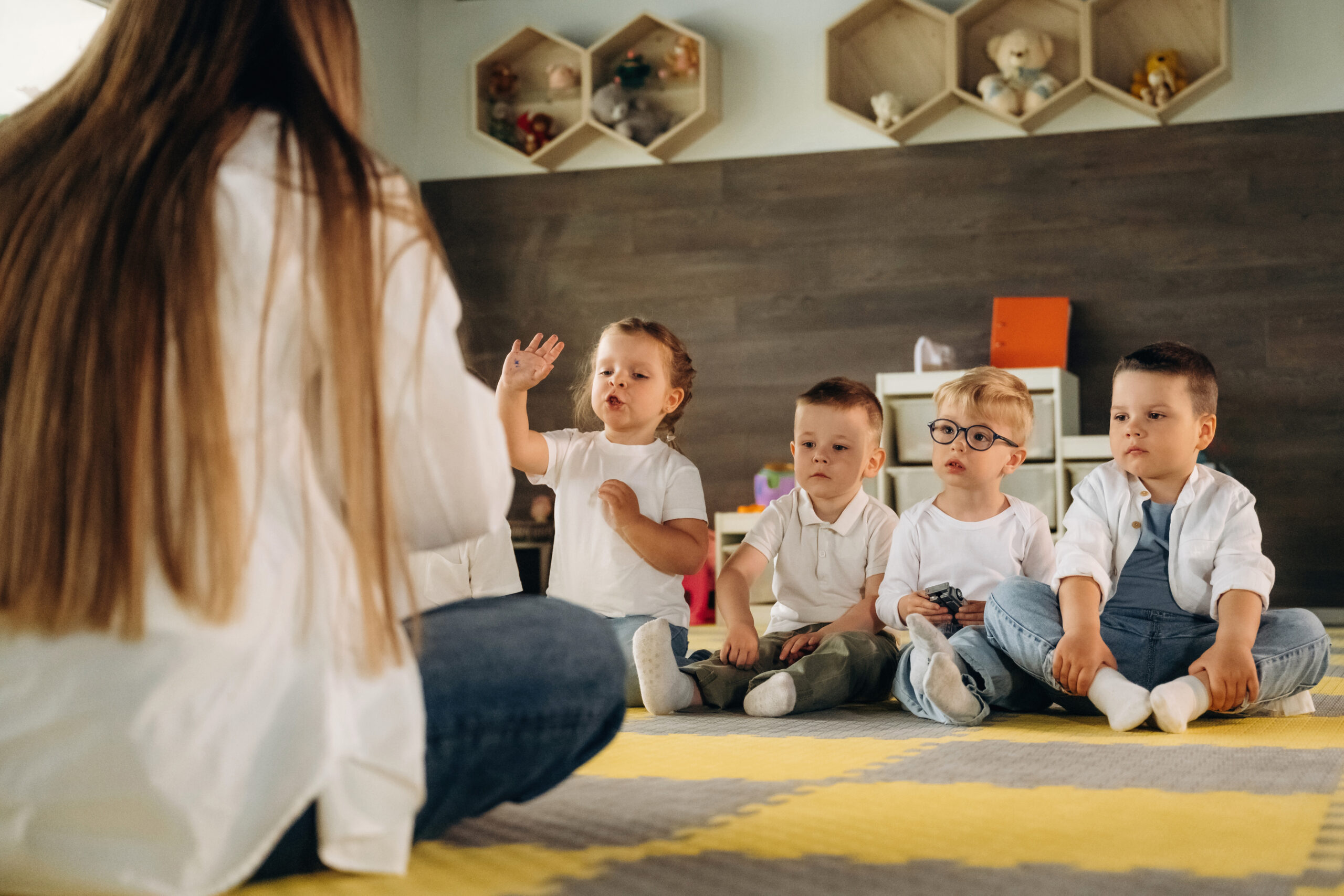 Teaching, sitting on the floor. Children in kindergarten with their teacher