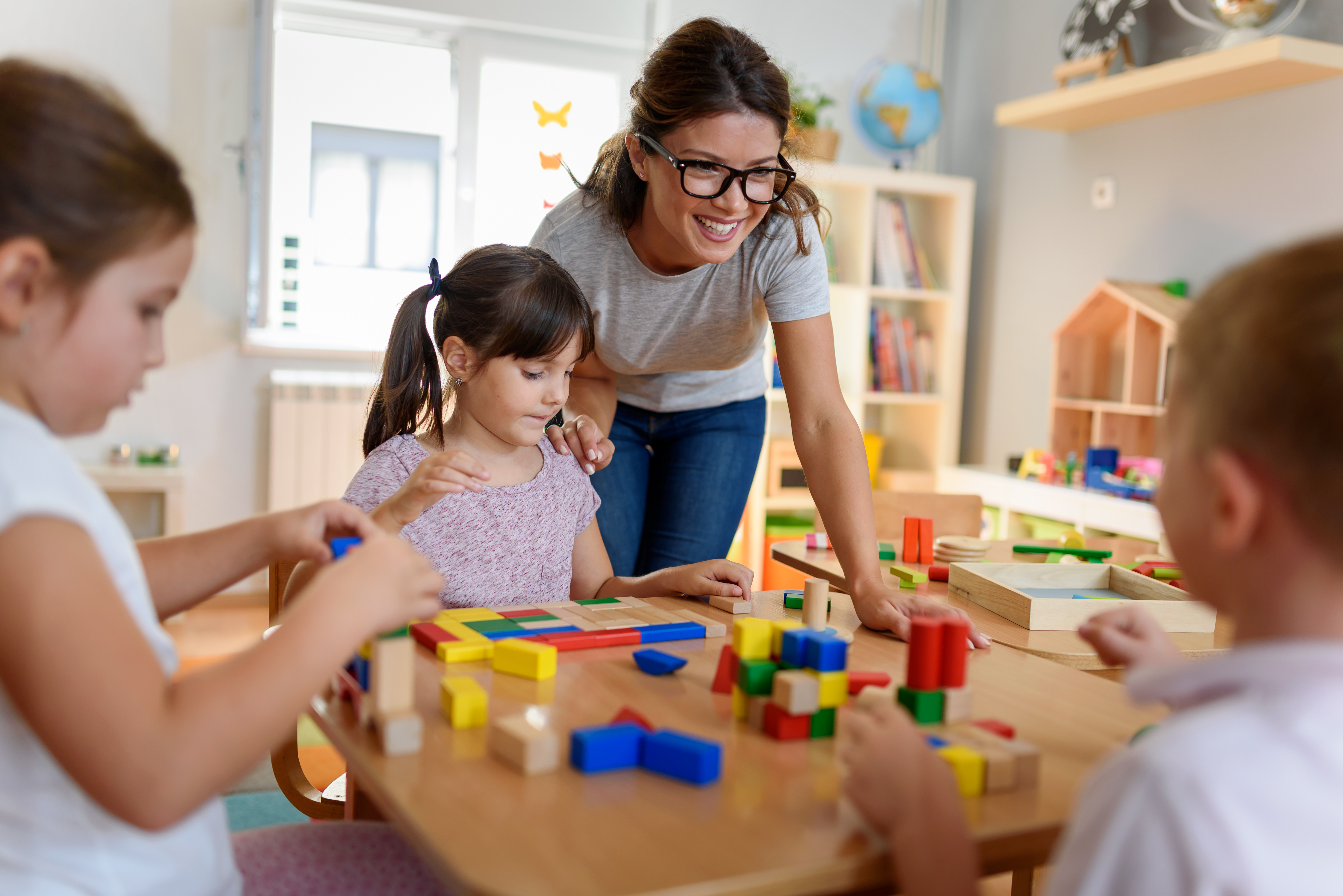 Preschool teacher with children playing with colorful wooden did