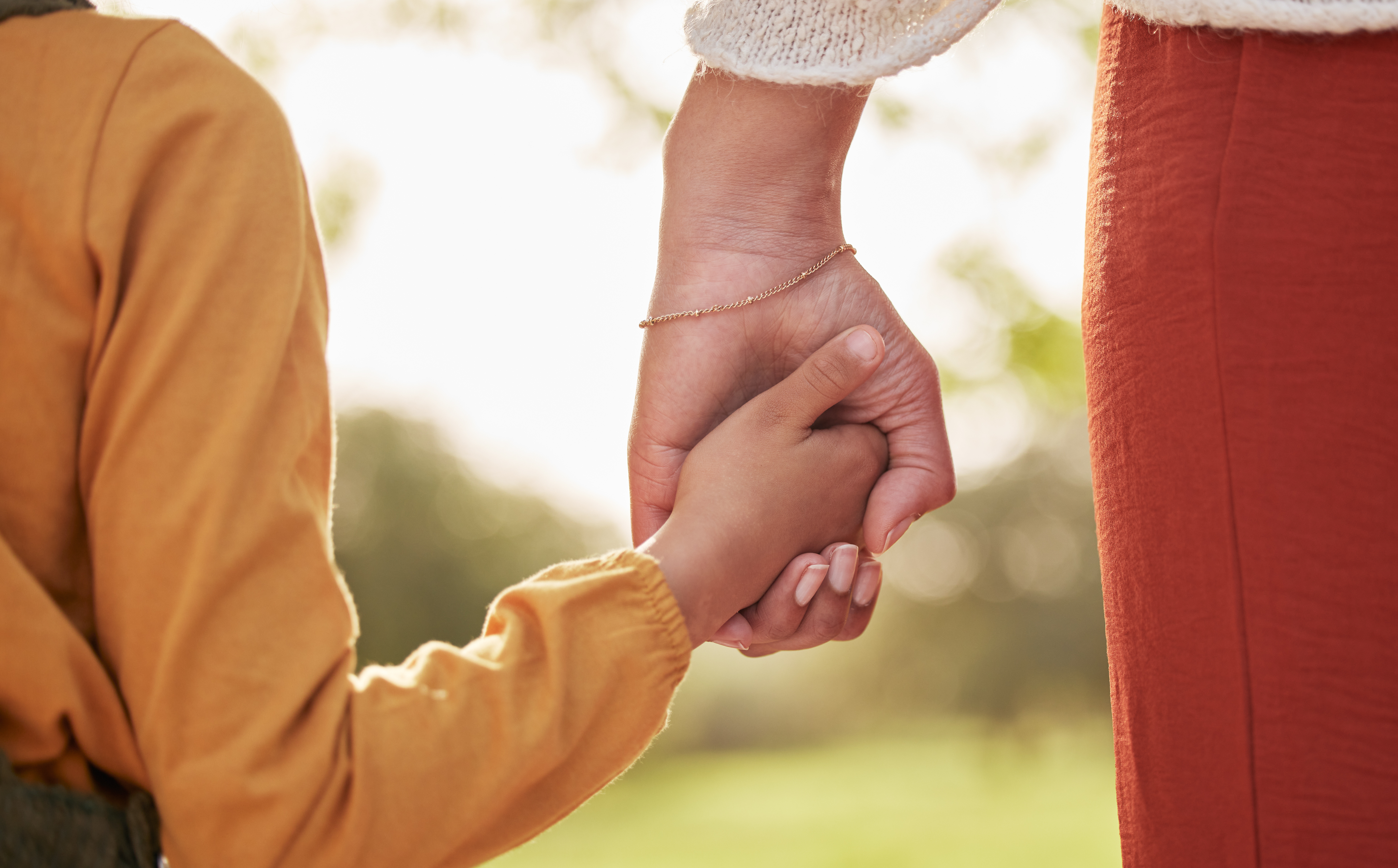 Mother, kid and holding hands for walking in park for support, trust and care together or bonding in nature. Love, comfort and parent help child in the morning sunshine with kindness on weekend